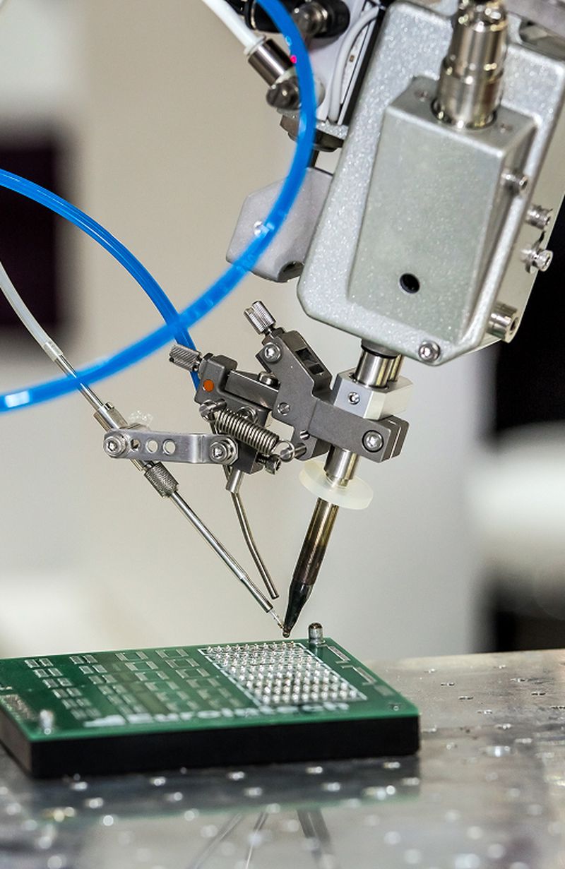 Close-up of automated semiconductor assembly equipment placing components on a printed circuit board